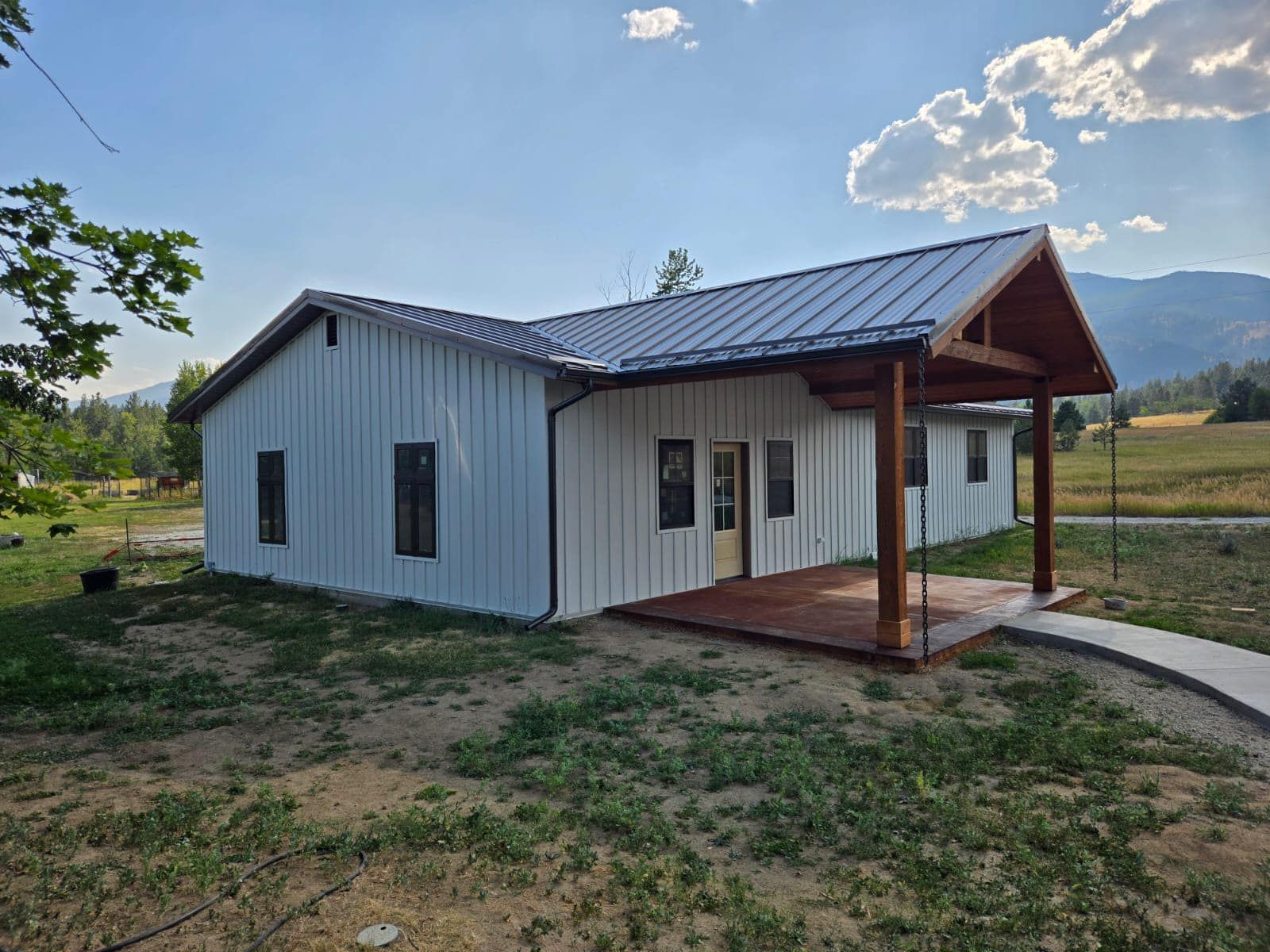 A white house with a metal roof and a wooden porch.