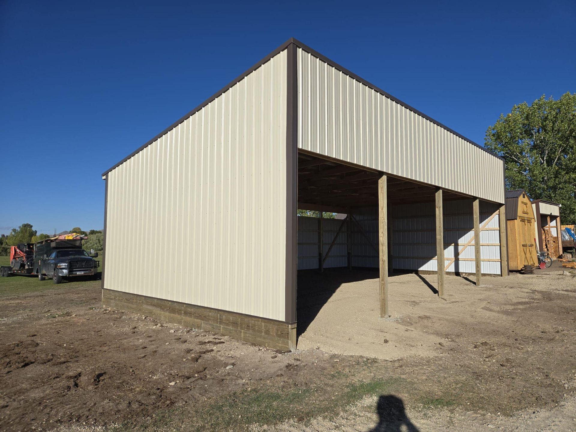 A white metal building is sitting in the middle of a dirt field.