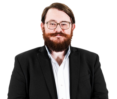 Smiling person with glasses and beard wearing a black blazer over a white shirt on a white background