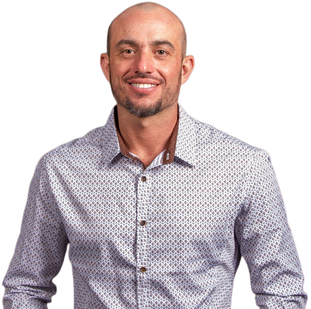 A bald man with a beard is wearing a patterned shirt and smiling