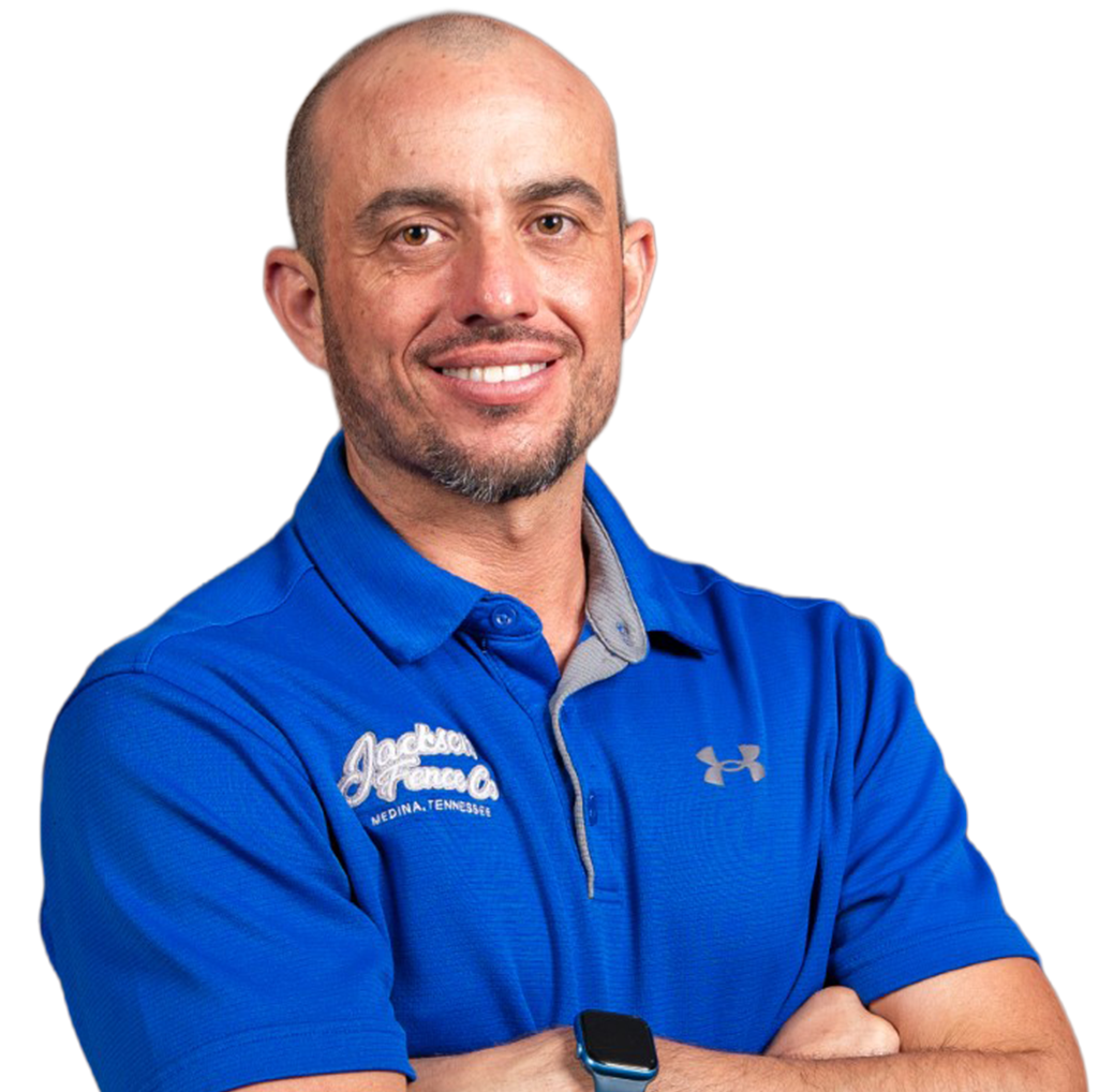 A man wearing a blue under armour shirt smiles with his arms crossed