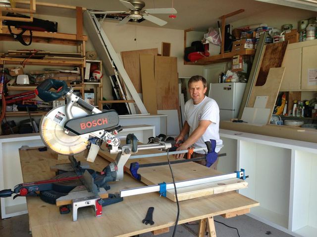 A man is using a bosch miter saw to cut a piece of wood.