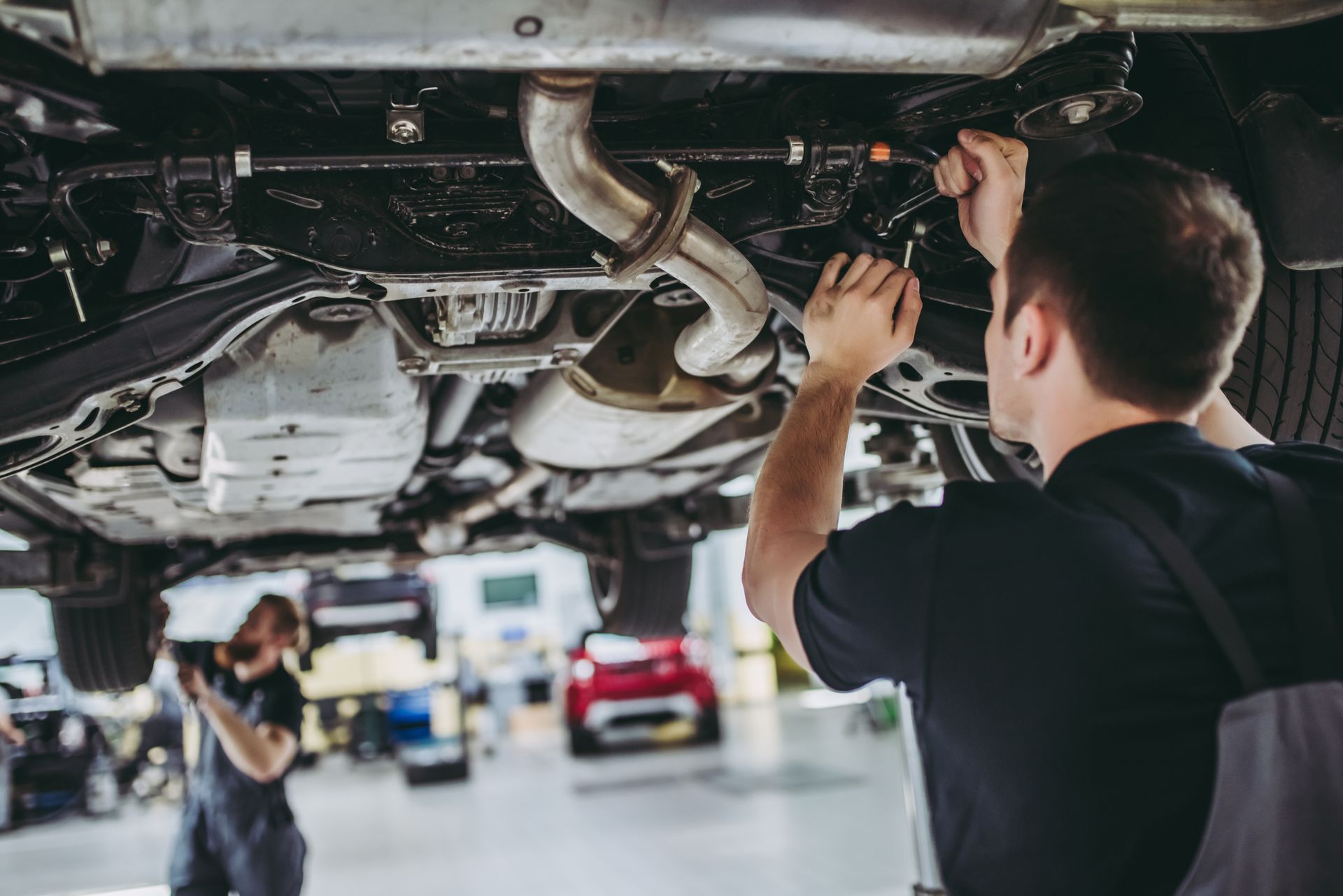 An auto maintenance mechanic inspecting a vehicle during service. An auto maintenance mechanic inspecting a vehicle during service.