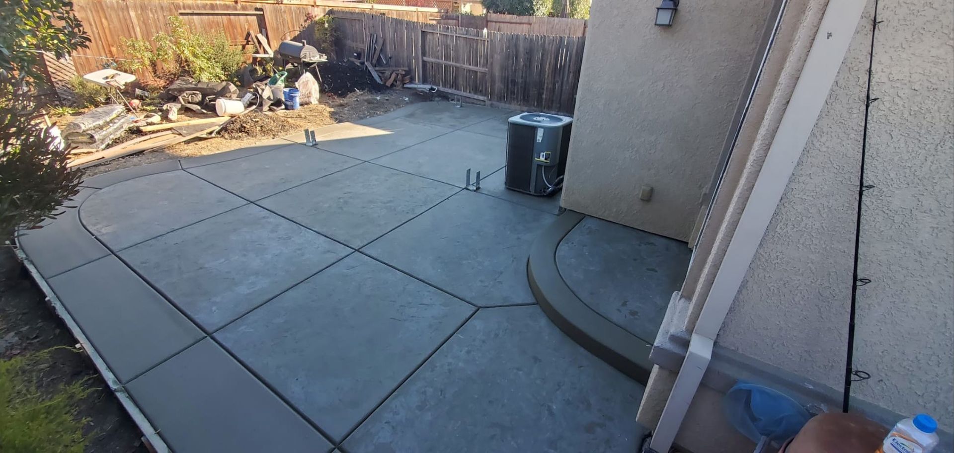 A concrete patio is being built in the backyard of a house.