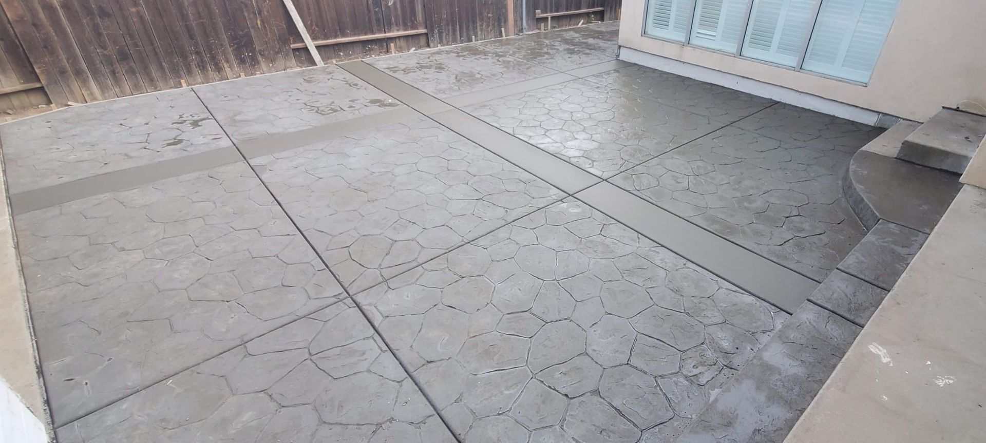 A concrete patio with a wooden fence in the background.