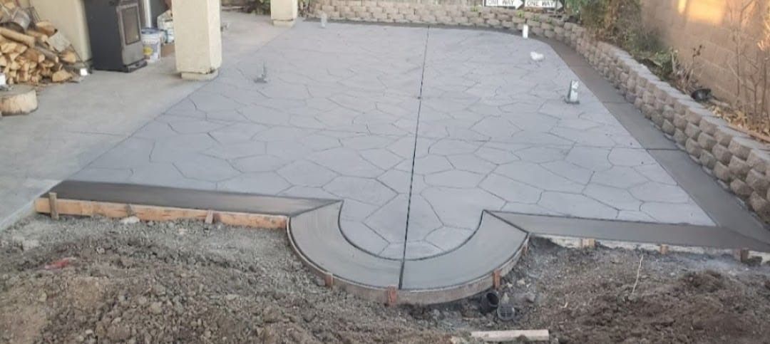 A concrete patio is being built in a backyard.