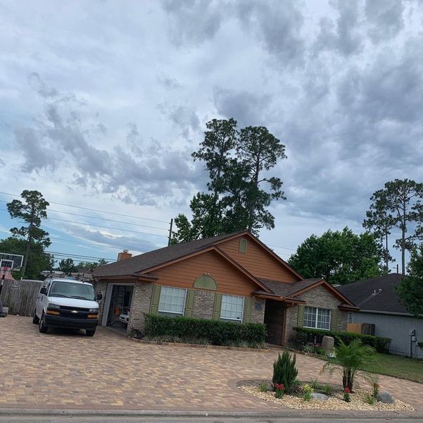 A white van is parked in front of a house on a cloudy day.