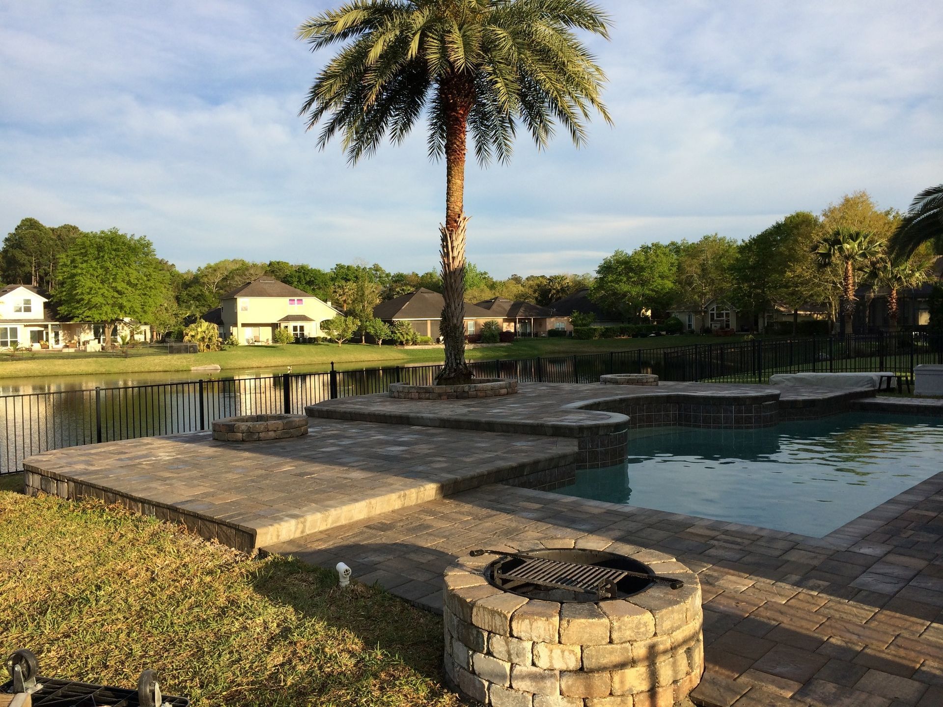 A swimming pool with a fire pit and a palm tree in the background