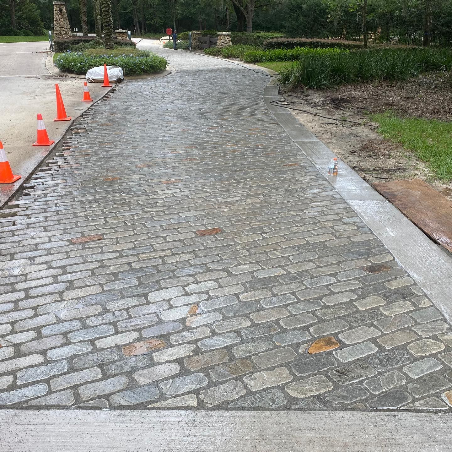 A cobblestone driveway with orange cones on the side