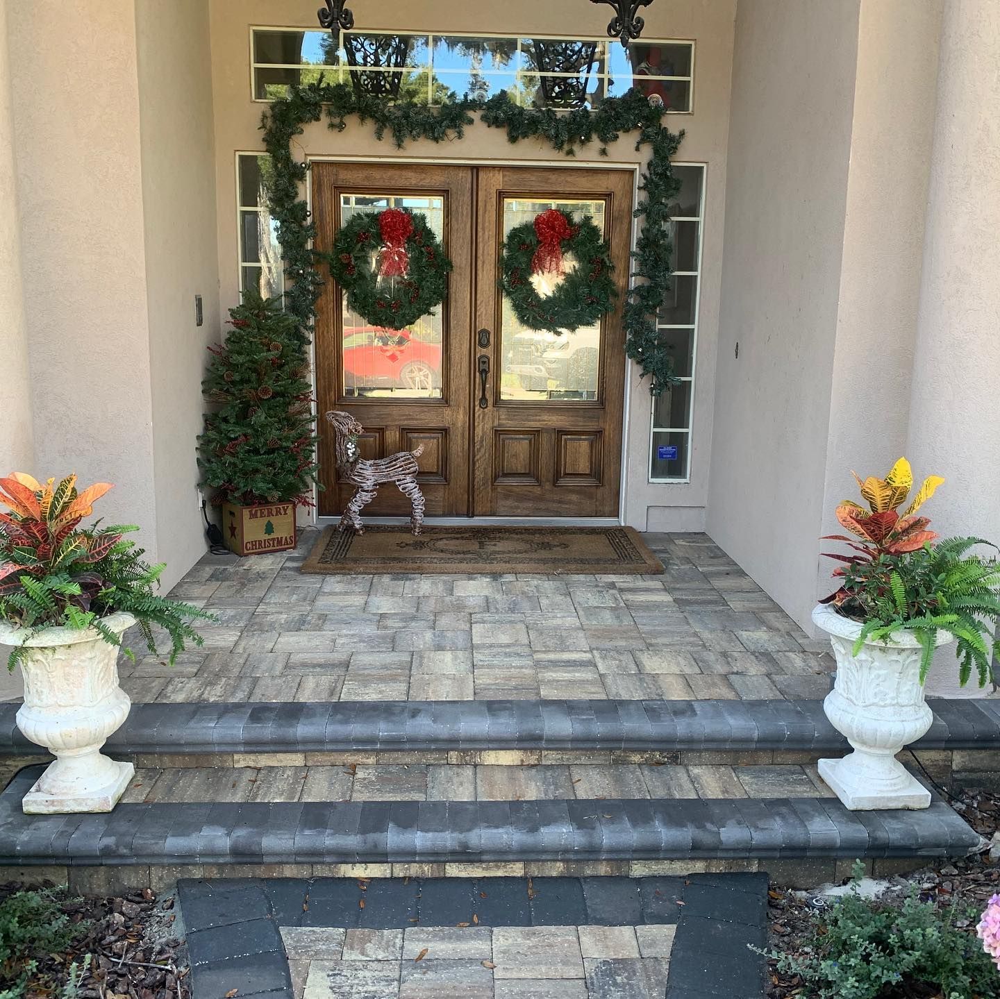 The front door of a house decorated for christmas with stone flooring.