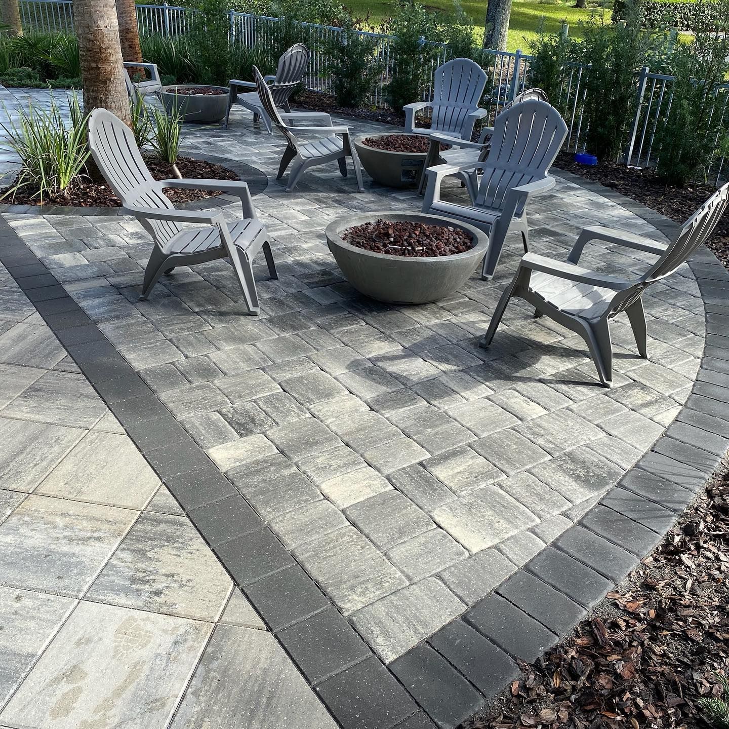 A patio with chairs , a fire pit and a bowl of mulch.