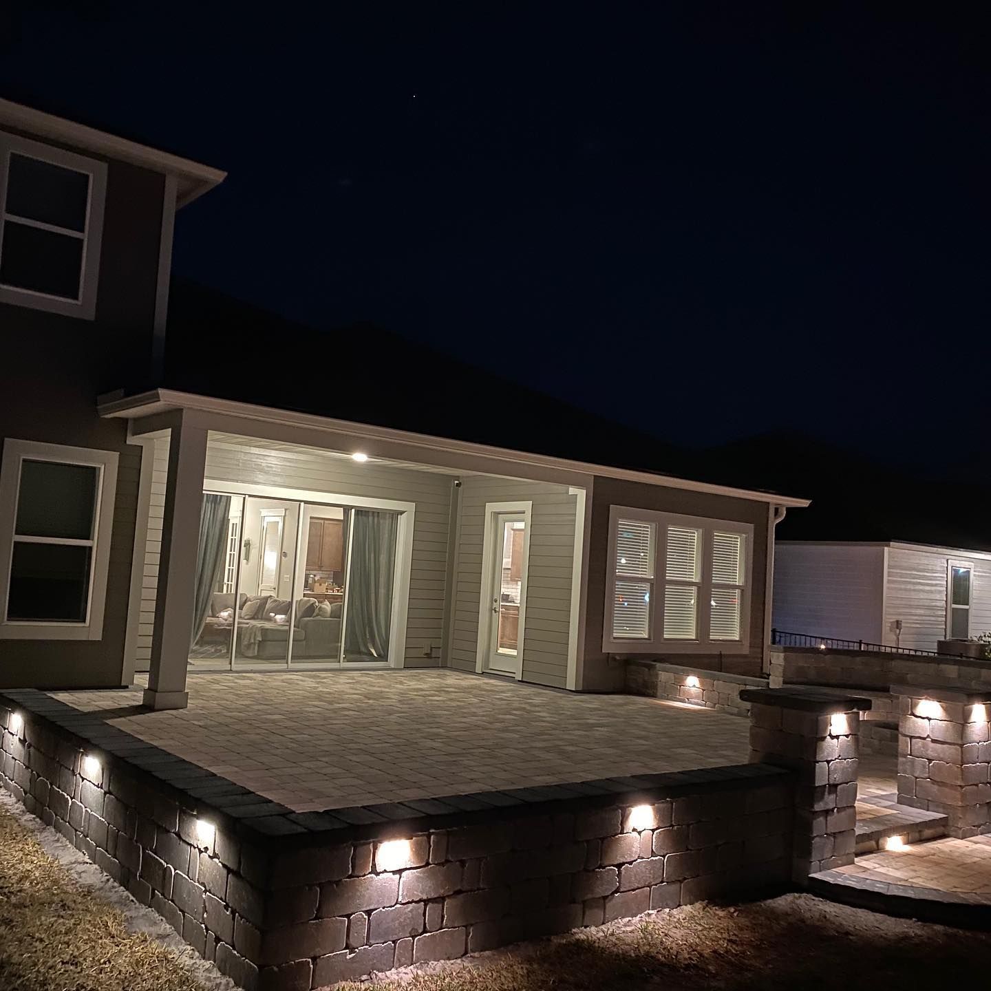 The backyard of a house is lit up at night.