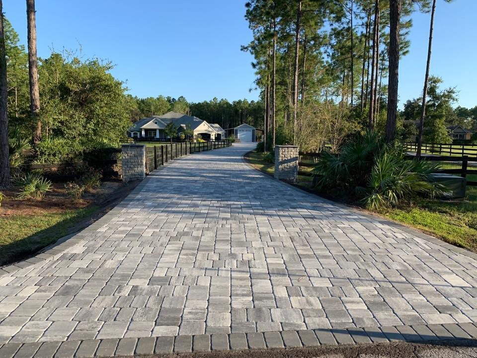 A brick driveway leading to a house surrounded by trees