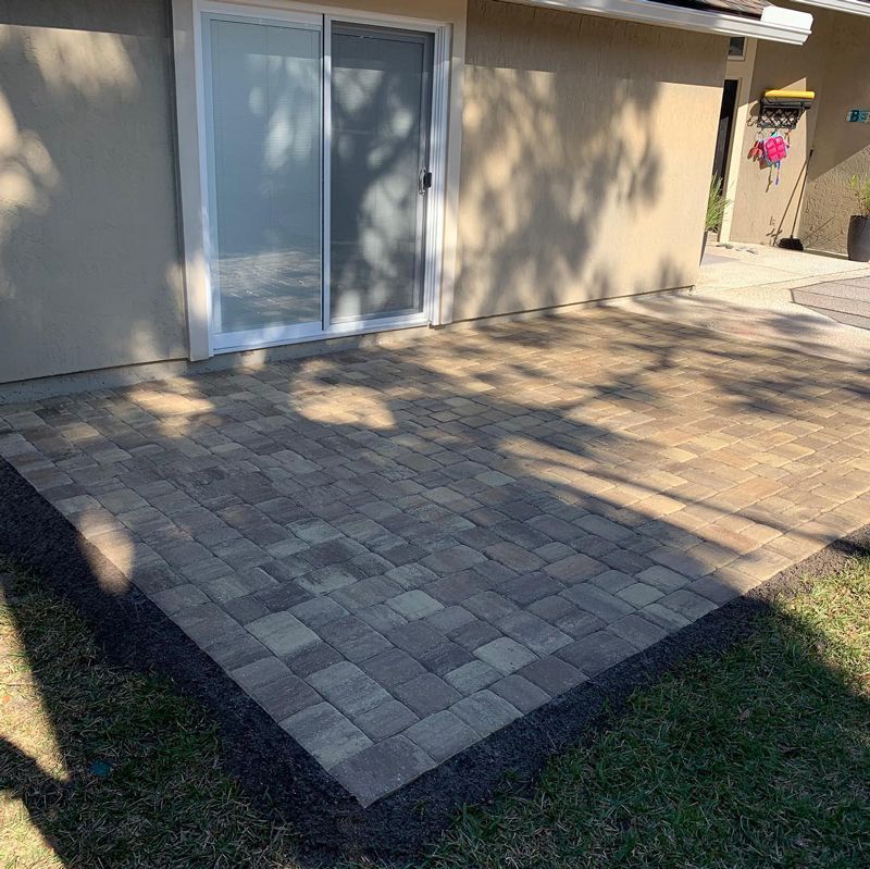 A brick patio in front of a house with a sliding glass door.