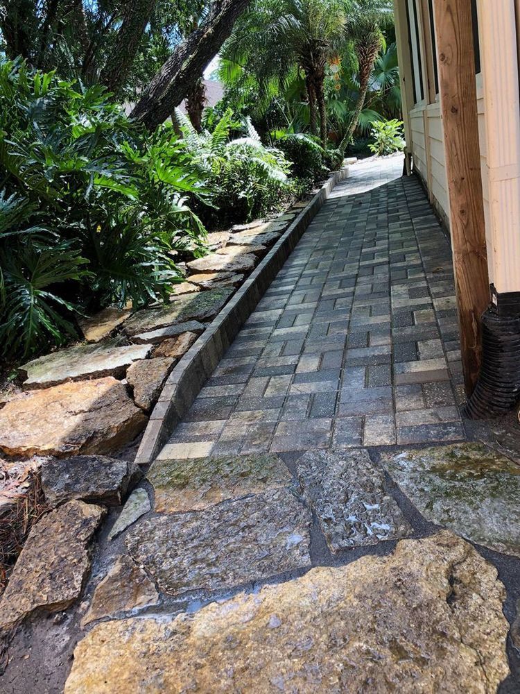 A stone pavement leading to a house in a garden.