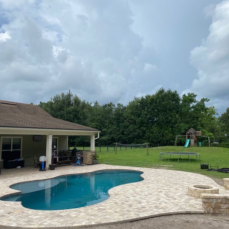 There is a large swimming pool in the backyard of a house.