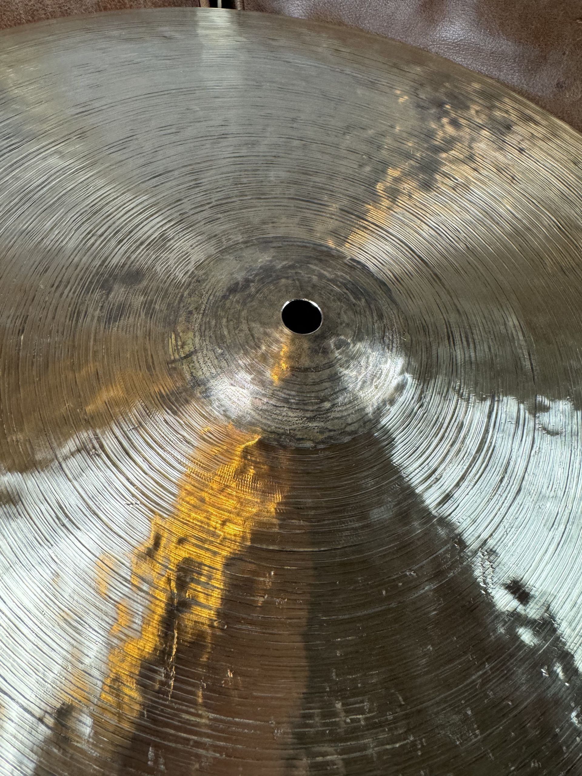 Close-up of a bronze-colored cymbal with circular grooves radiating from a center hole.