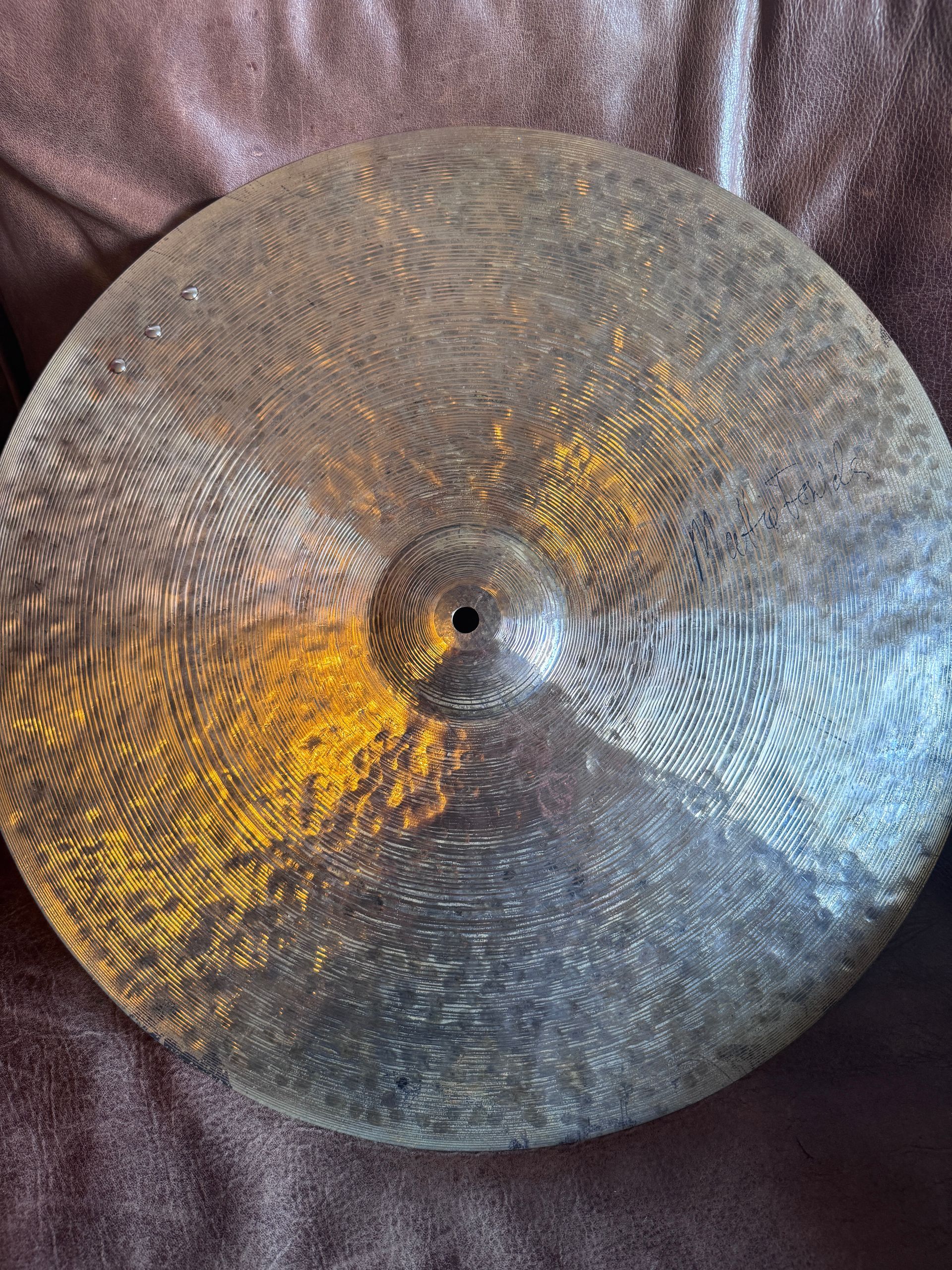 Close-up of a dark cymbal with textured patterns, displaying colors like silver, gold, and black.