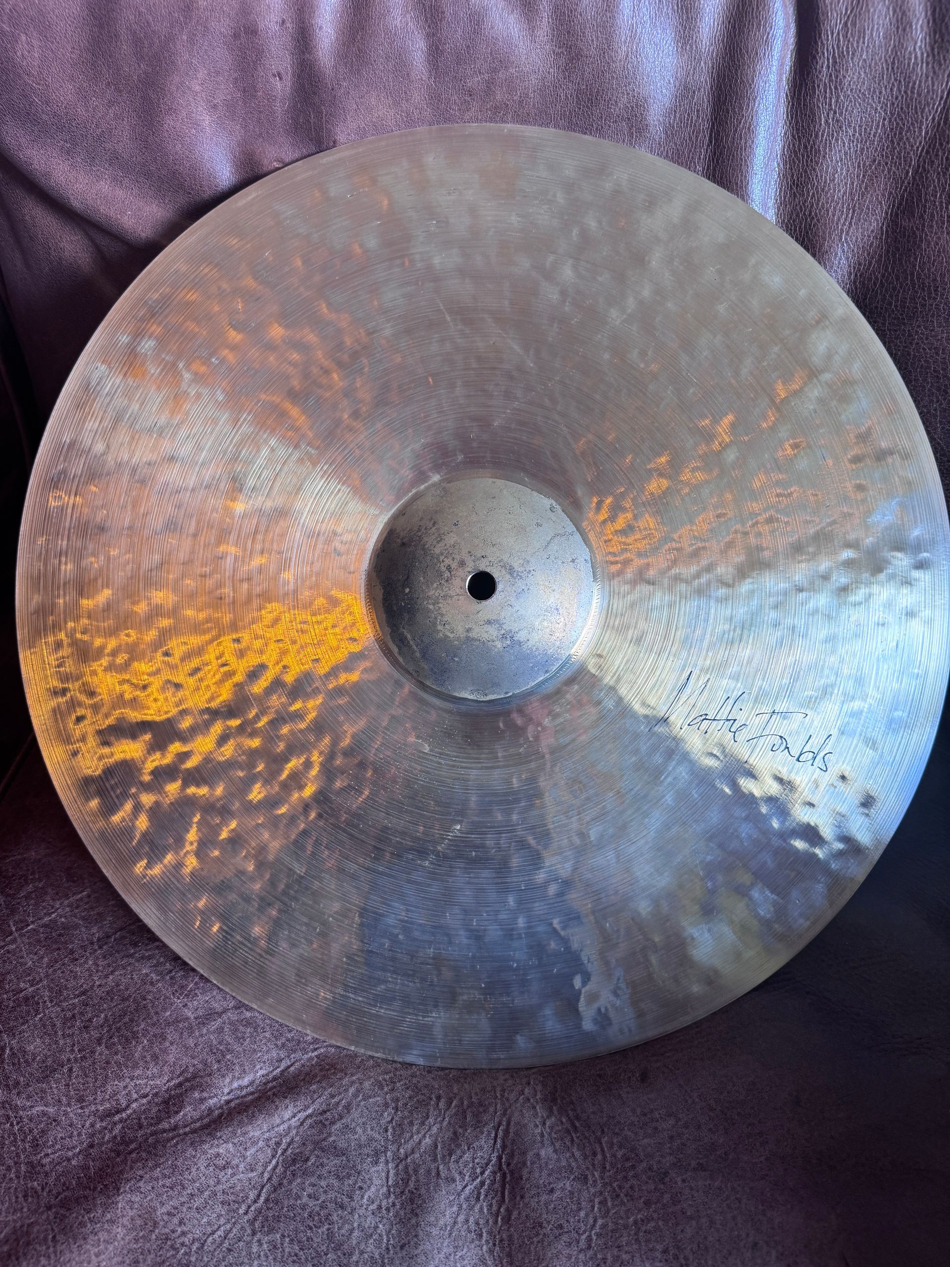A dark, tarnished bronze cymbal with a central hole.