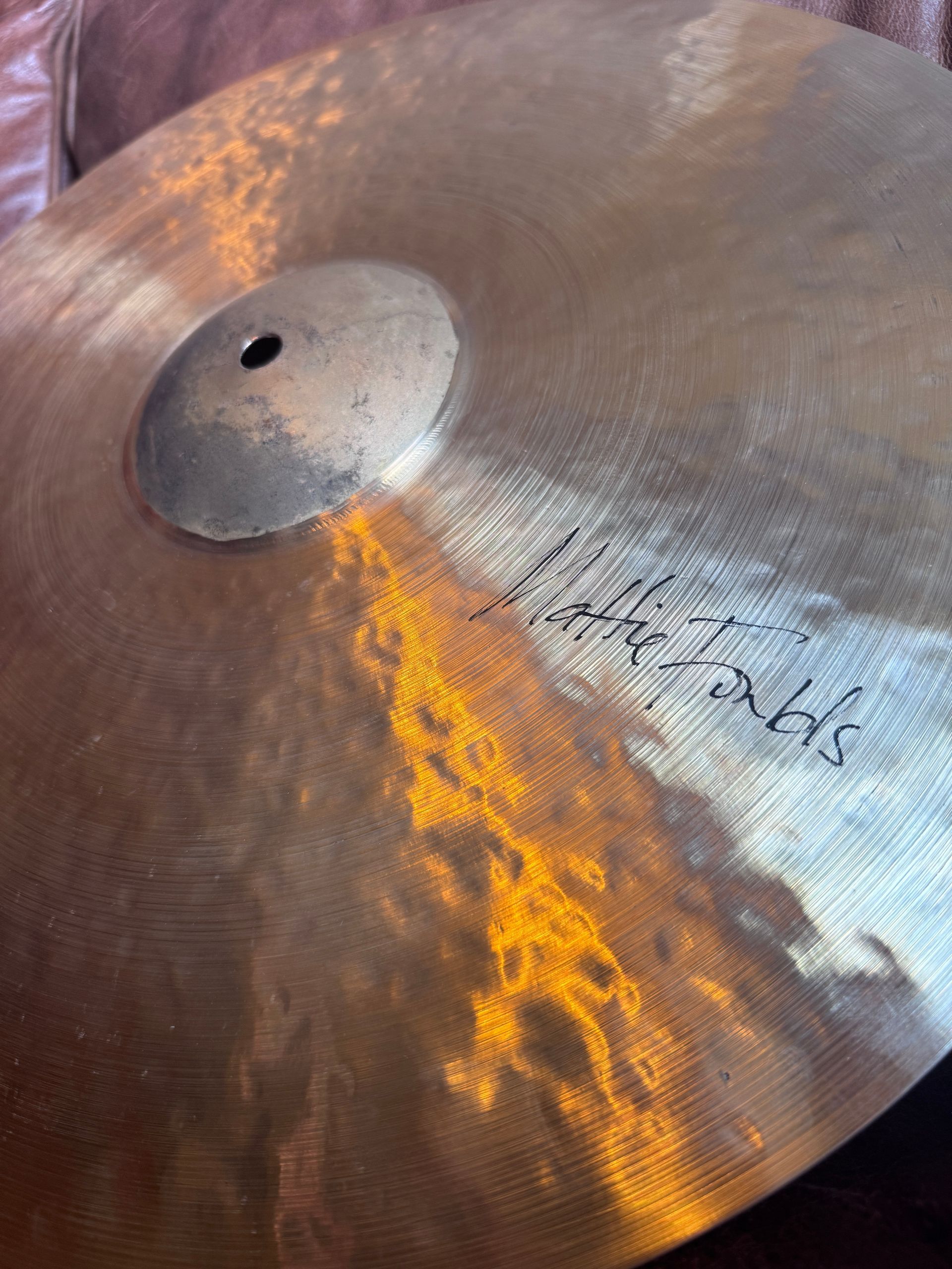Close-up of a well-used bronze cymbal with a signature on it.
