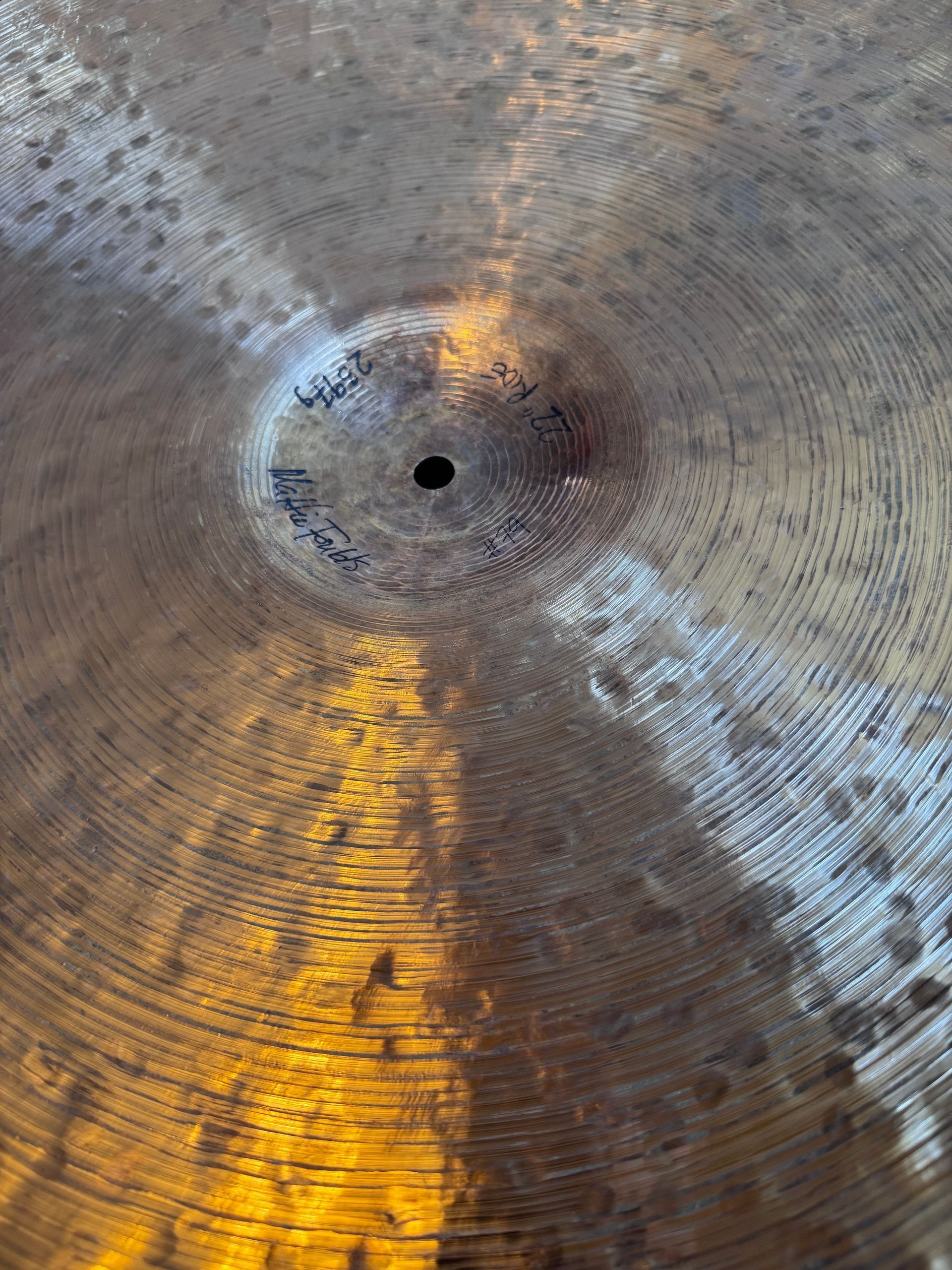 Close-up of a bronze cymbal with concentric grooves, central hole, and some oxidation.