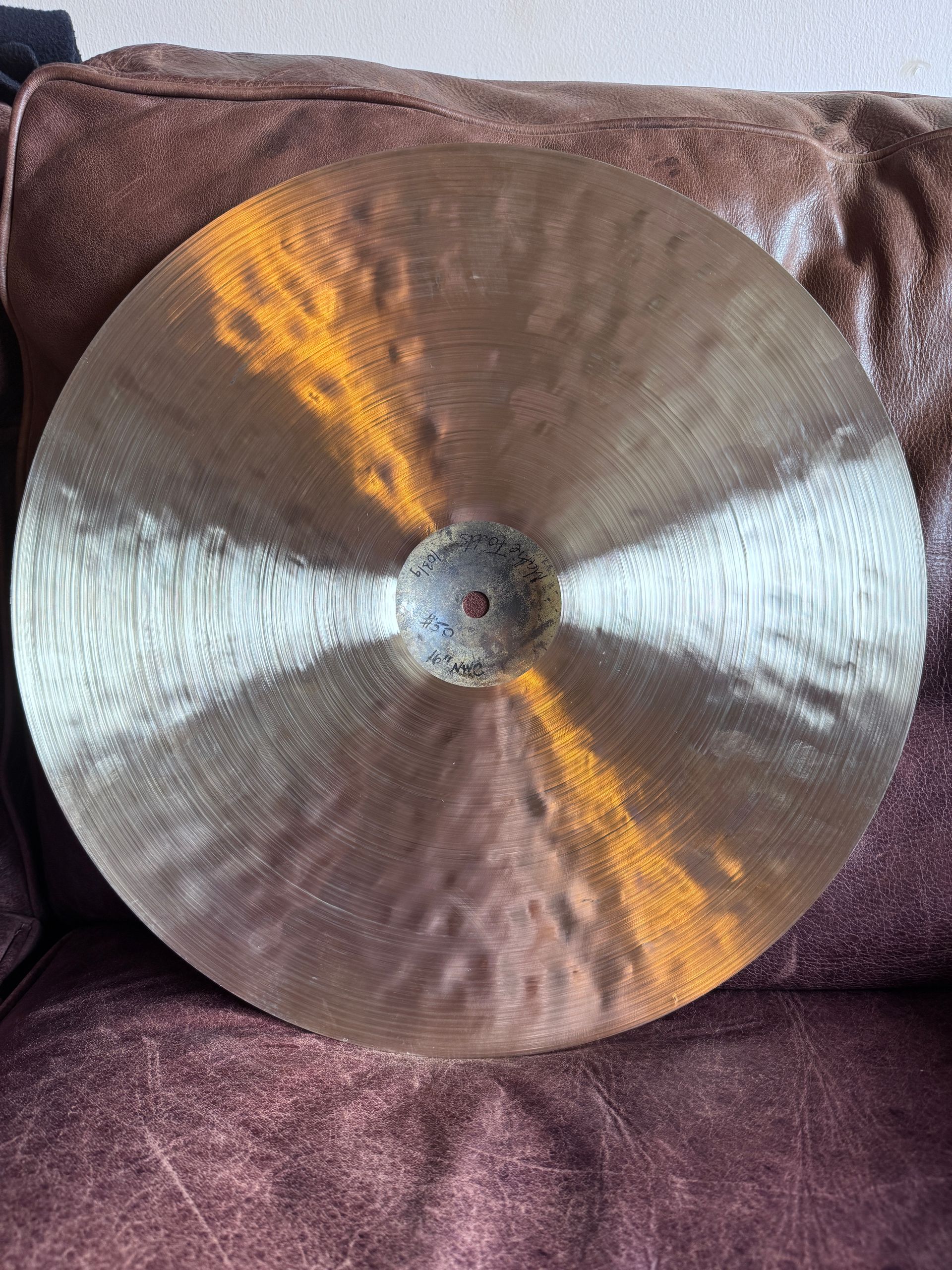 Bronze cymbal on a dark purple cushion.