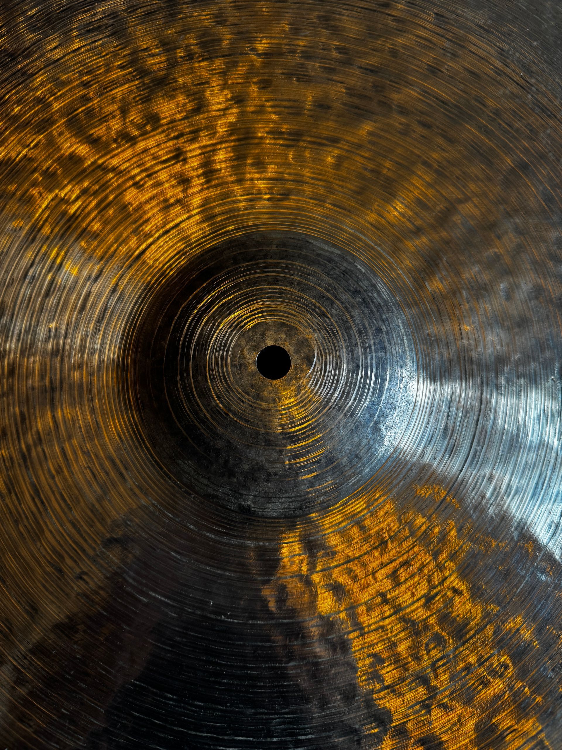 Bronze cymbal with a central hole, showing circular patterns and yellow-gold highlights.