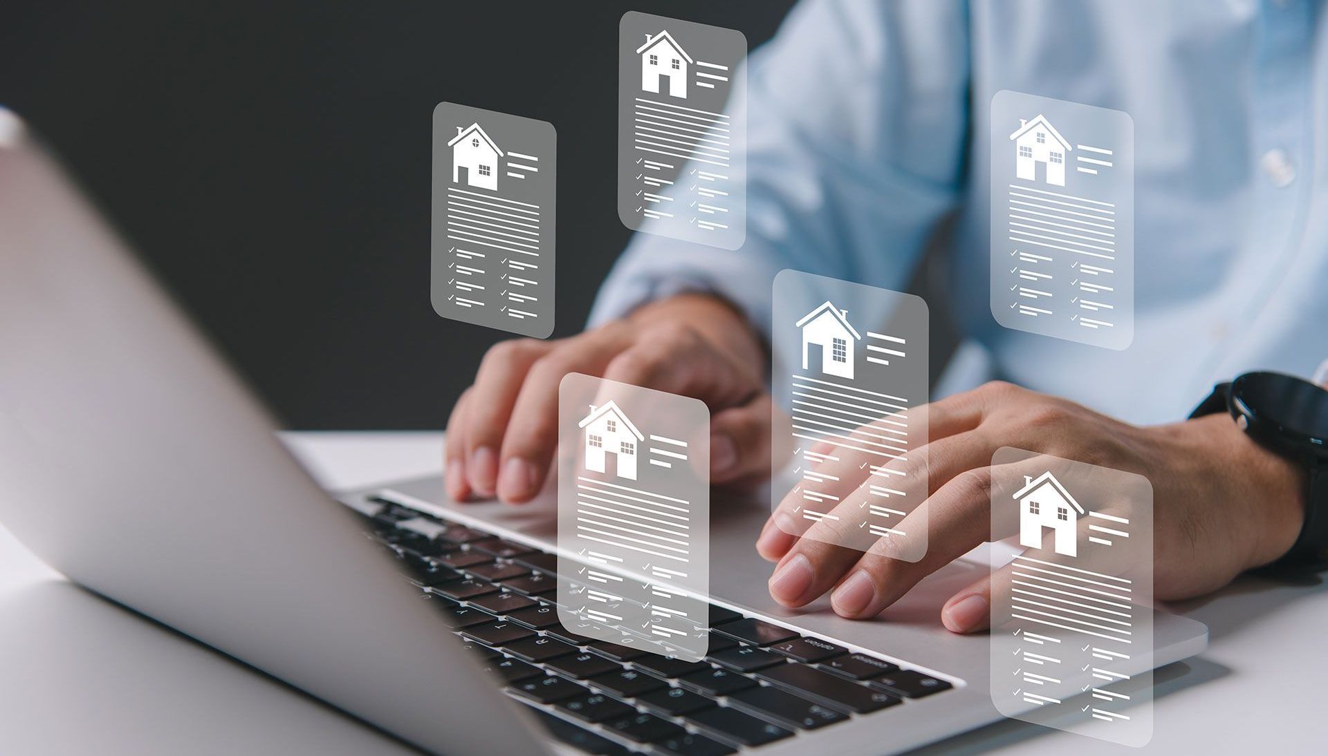 A man is typing on a laptop computer with houses coming out of the screen.