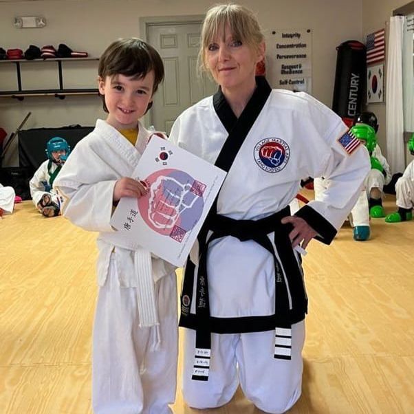 A woman and a boy in martial arts uniforms pose for a picture