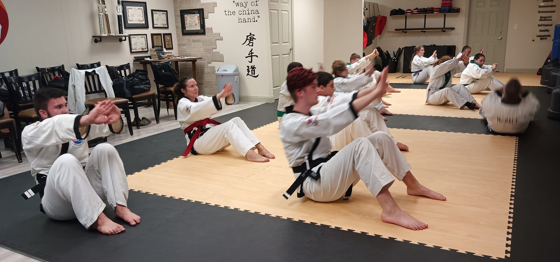 A group of people are doing exercises on a mat in a gym.