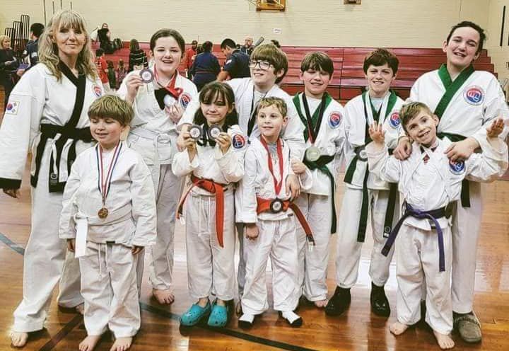 A group of children in martial arts uniforms are posing for a picture.