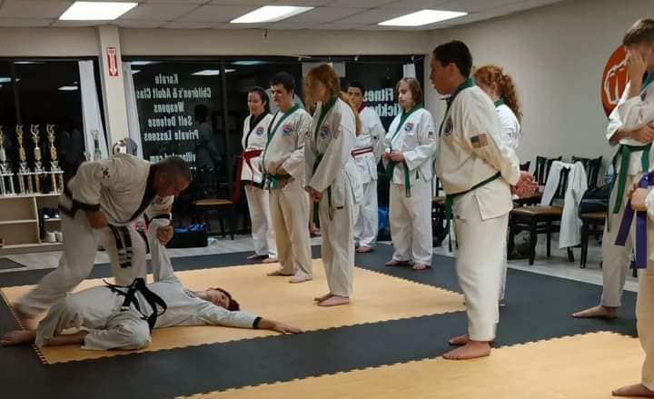A group of people are practicing martial arts in a gym.