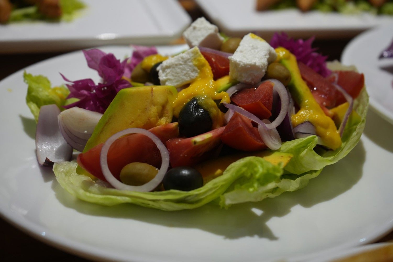 A close up of a salad on a white plate on a table.