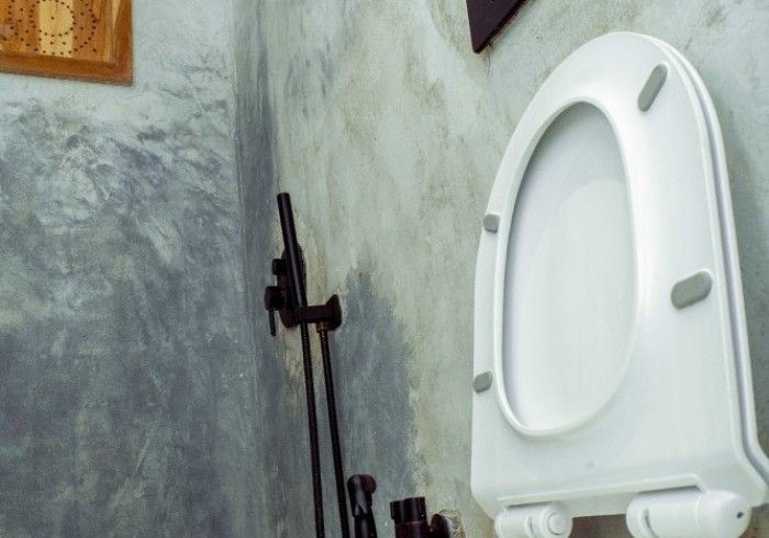 A white toilet is sitting in a bathroom next to a wall.