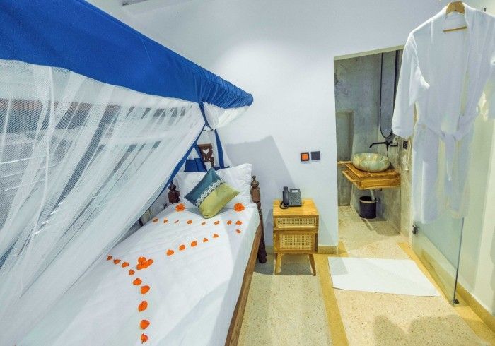 A bedroom with a single bed and a bathroom with a sink.
