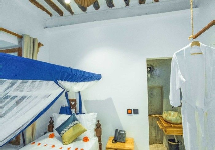 A bedroom with a canopy bed and a robe hanging from the ceiling.