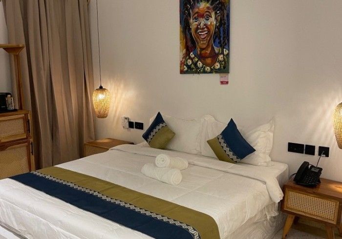 A hotel room with a bed and a painting on the wall.