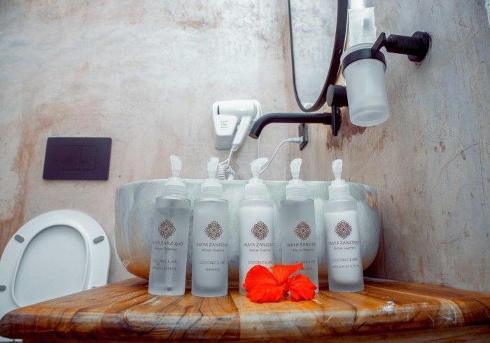 A bathroom with a sink , toilet , mirror and bottles of soap.