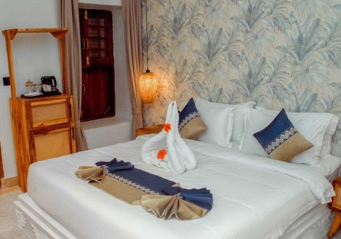 A hotel room with a bed and a swan made out of towels