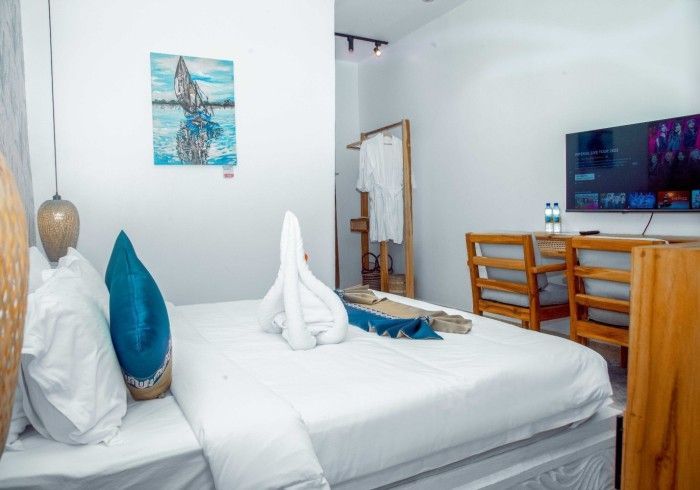 A hotel room with a bed , television , desk and chairs.