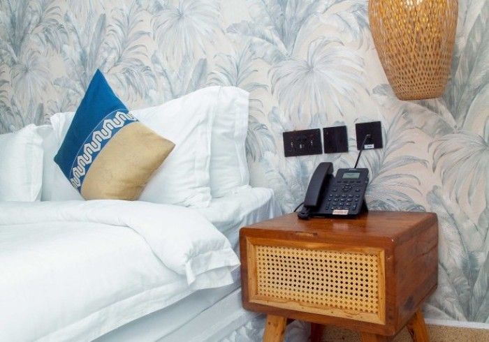 A hotel room with a bed , nightstand and telephone.