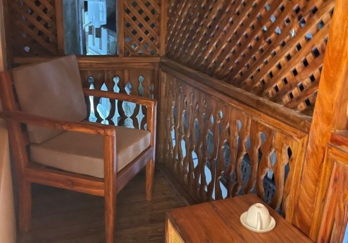 A wooden balcony with a chair and a table