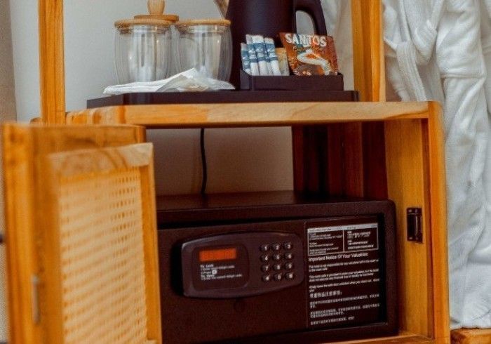A wooden shelf with a safe and a kettle on it.
