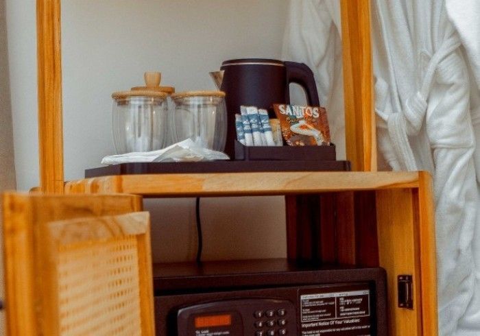 A hotel room with a safe , microwave , and coffee pot.