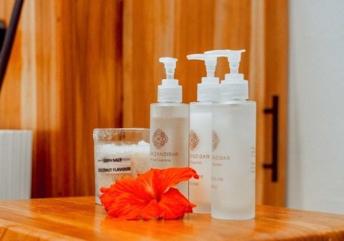 A wooden table topped with bottles of lotion and a flower.