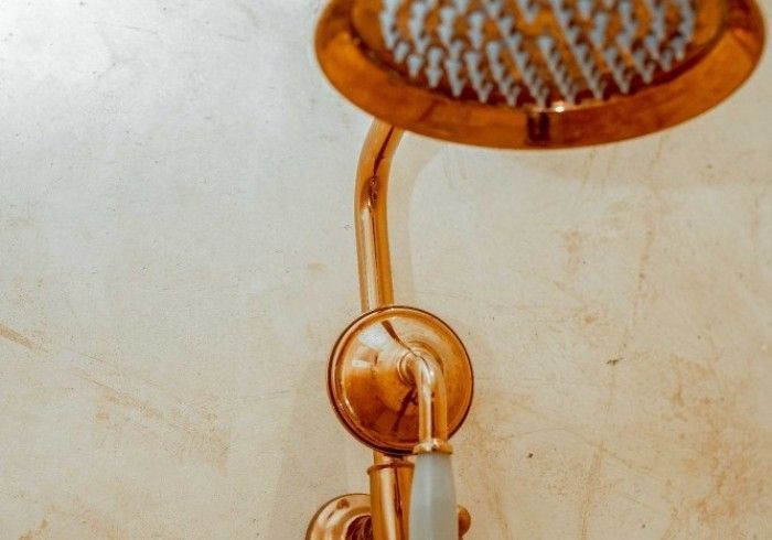 A gold shower head with a white hose attached to it