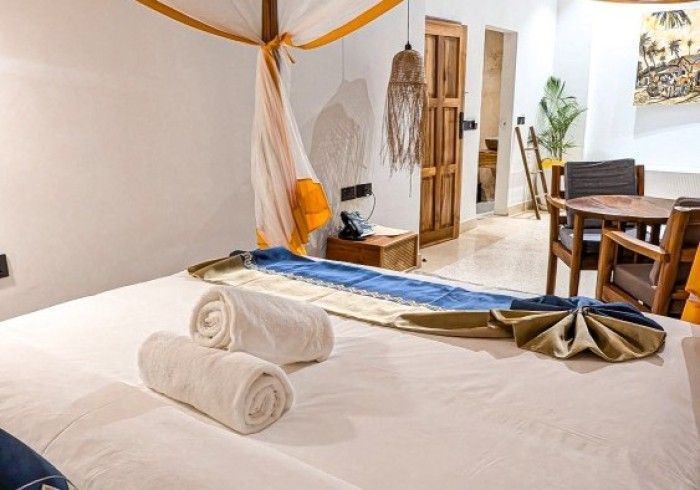 A hotel room with a canopy bed and a table and chairs.