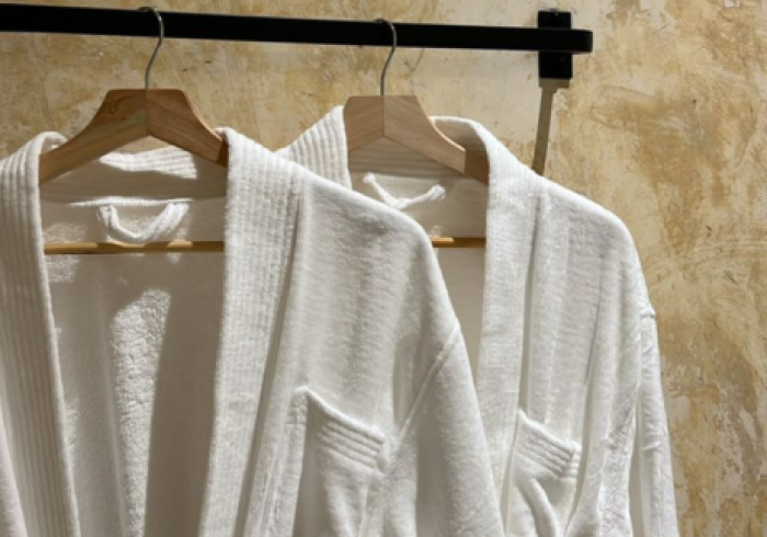 Two white bathrobes are hanging on a rack.