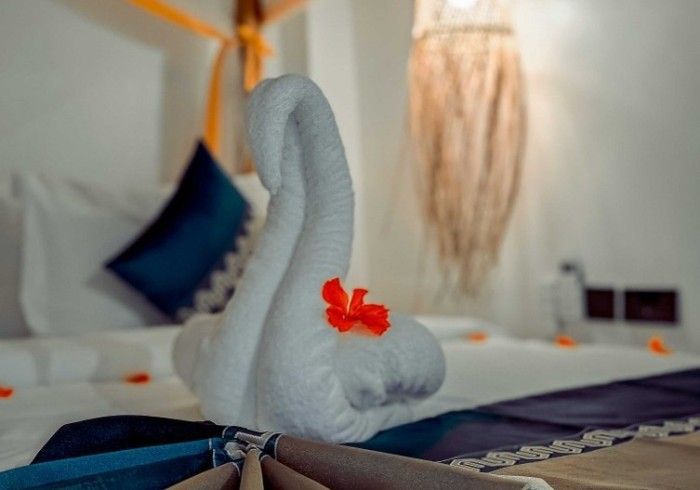 A swan made out of towels is sitting on top of a bed.