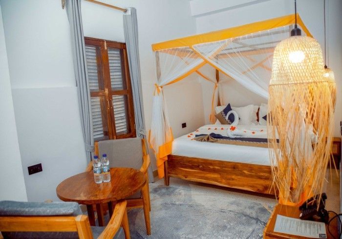 A bedroom with a canopy bed , a table and chairs.